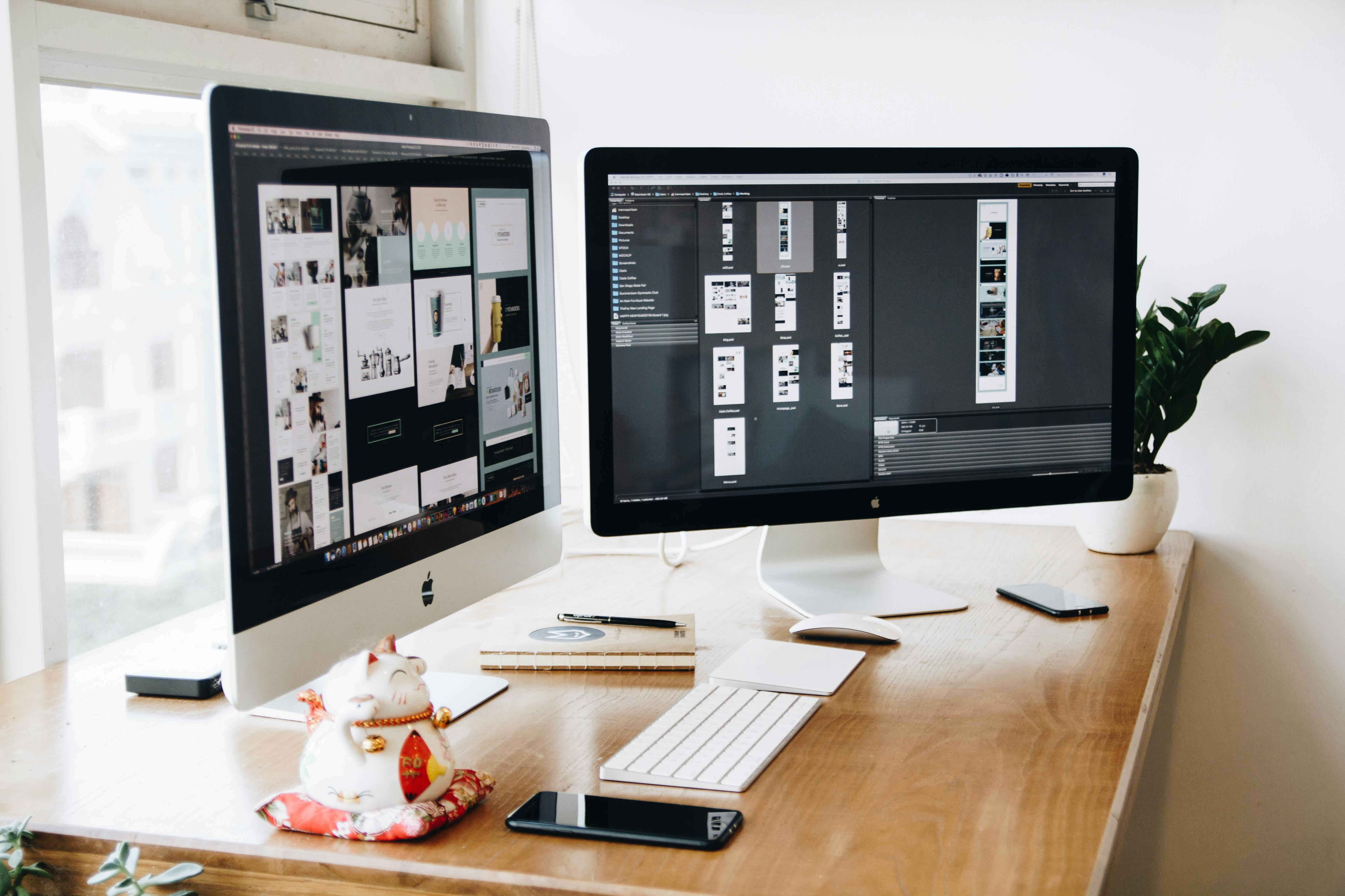 Professional web development workspace with dual monitors showing design work